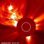 l’éjection de matière coronale du 4 janvier 2002 vue par SOHO. Autant en emporte le vent solaire. Le cercle blanc au centre de l’image réprésente le disque de notre étoile, masqué par le coronographe de l’instrument LASCO. Sans ce masquage, l’éclat du Soleil éblouirait le télescope et ne nous permettrait pas d’obtenir des images aussi détaillées de l’environnement solaire.